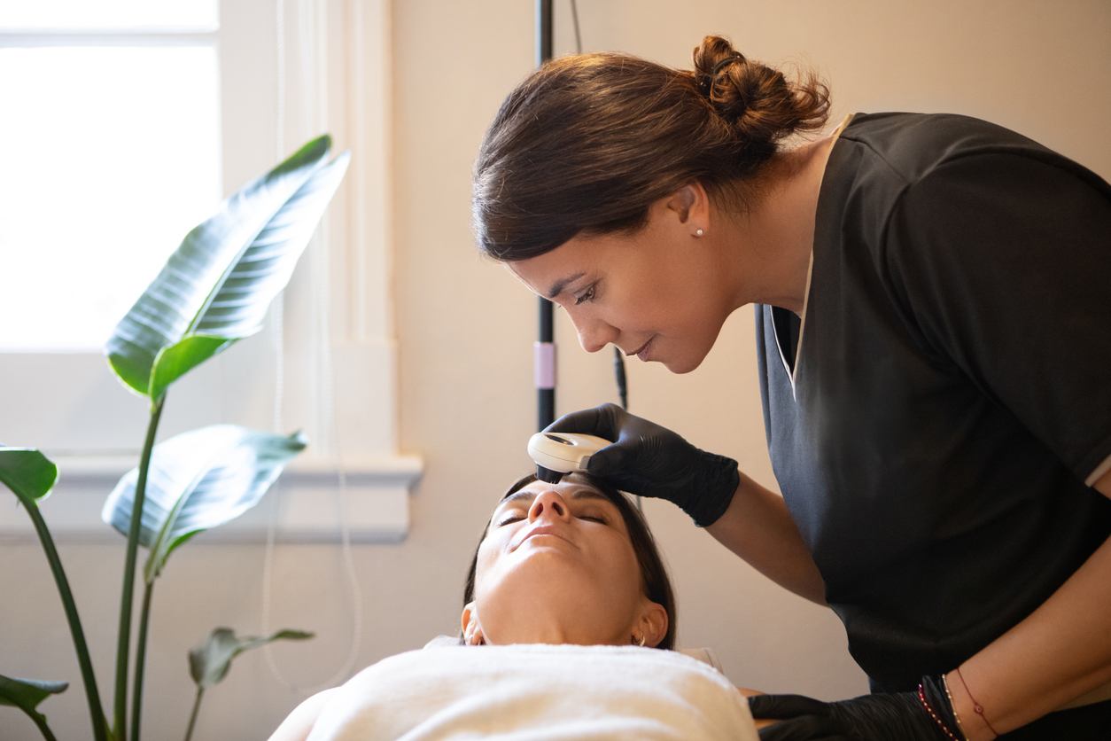 Esthetician performing a facial treatment on a client in a spa setting.