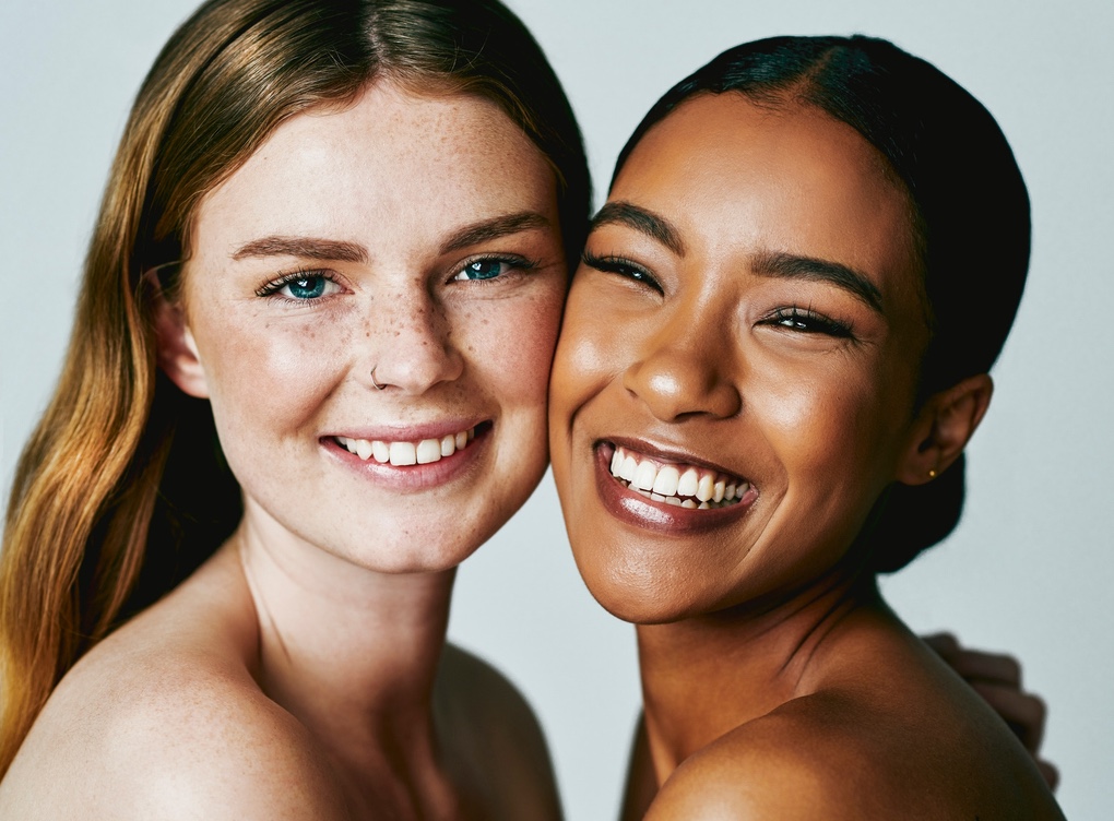 Two women smiling closely together in a warm portrait.