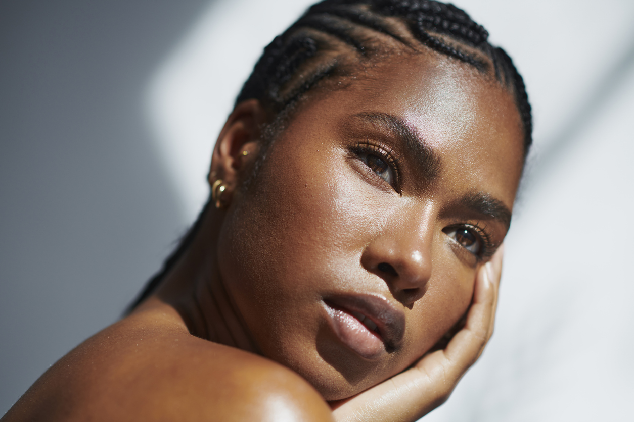 A woman with braided hair and thoughtful expression in soft lighting.